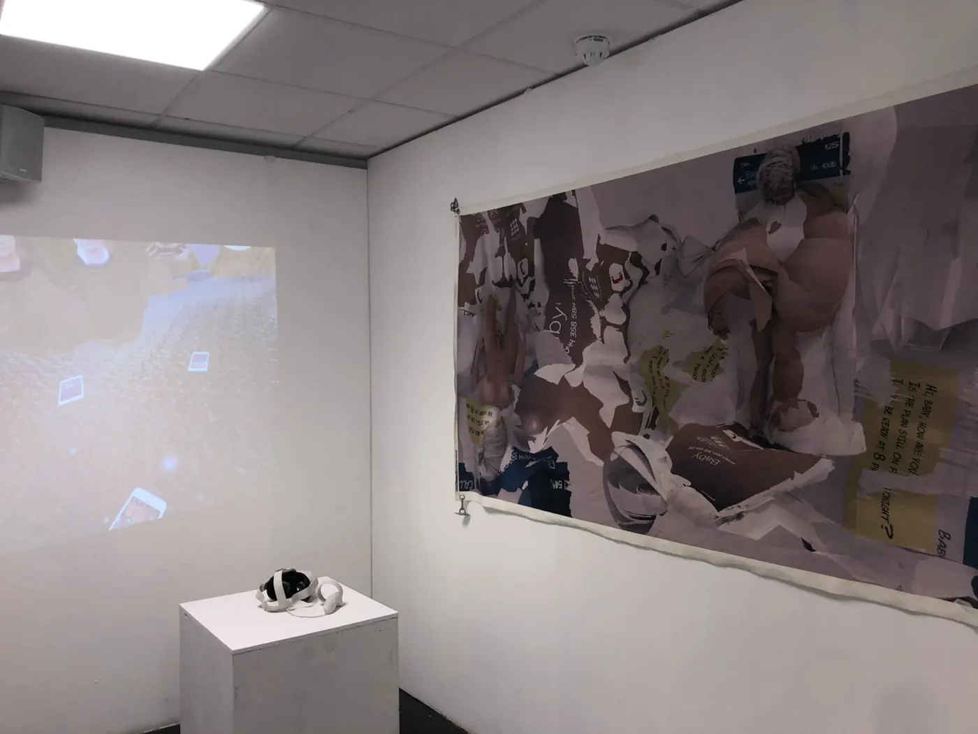 Gallery installation with a projected render, a small sculpture on a plinth and a large collaged print on the wall